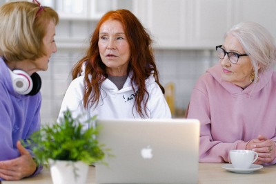 Three women talking around a laptop