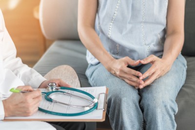 woman sitting in front of doctor with clipboard